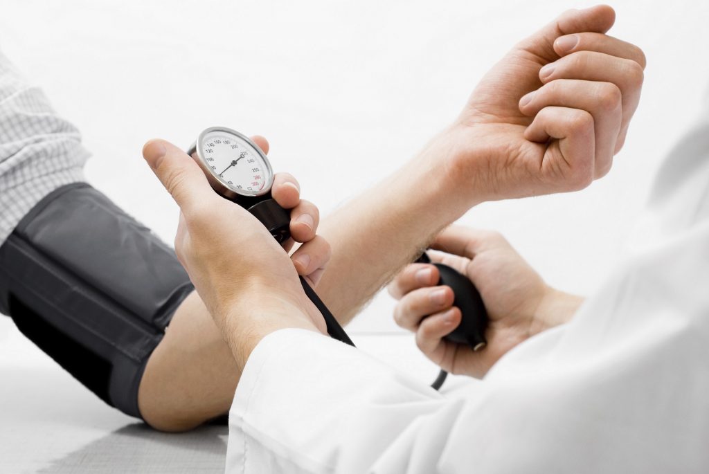 Doctor measuring blood pressure - studio shot on white background