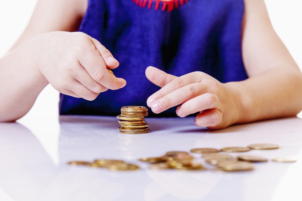 Teaching kid Business. Start financial education of cute little child girl with coins. Wealth, money, cash, success, kids financial literacy concept.